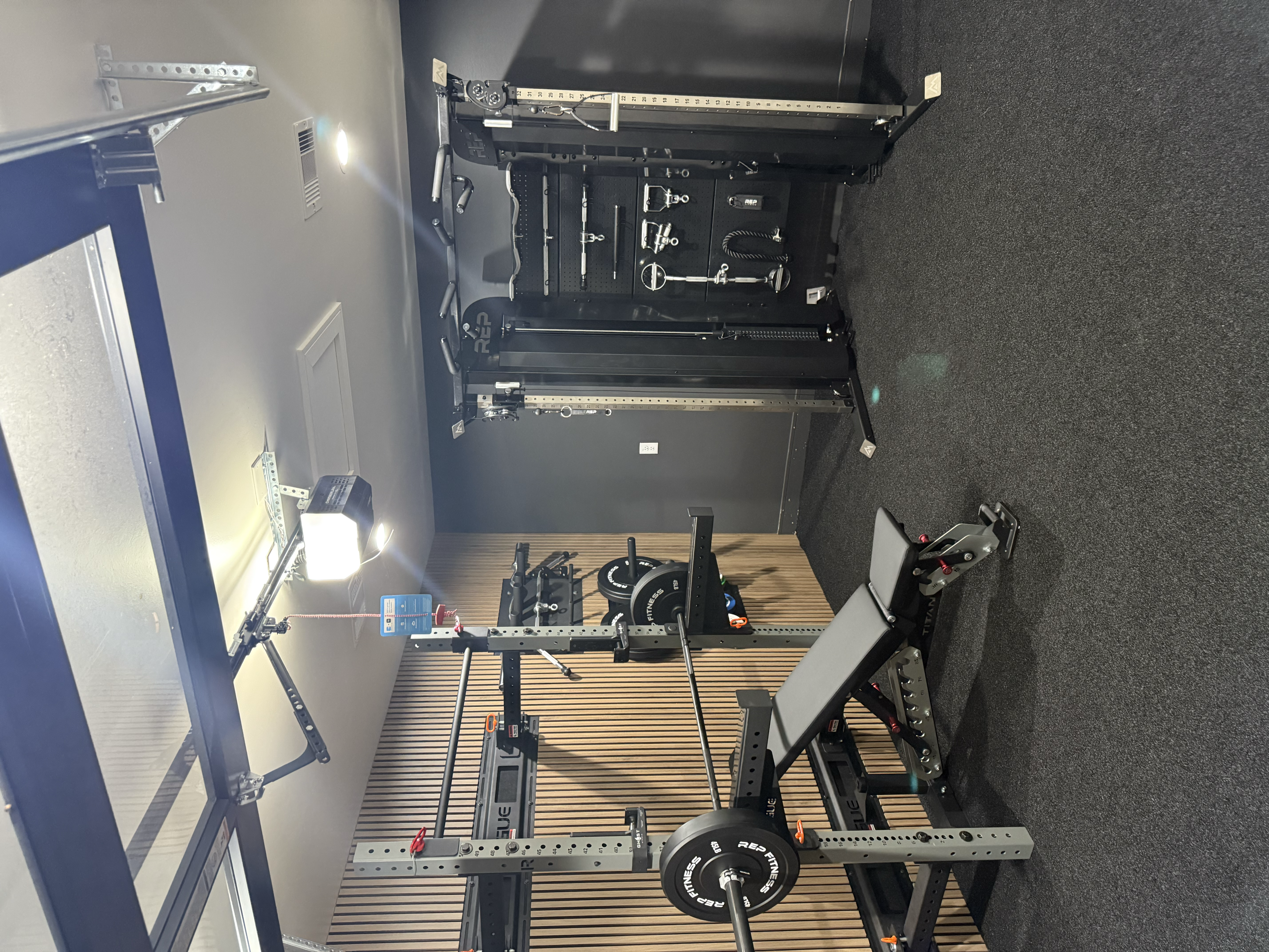 Modern garage gym with wood slat walls, a power rack, bench, and cable machine.